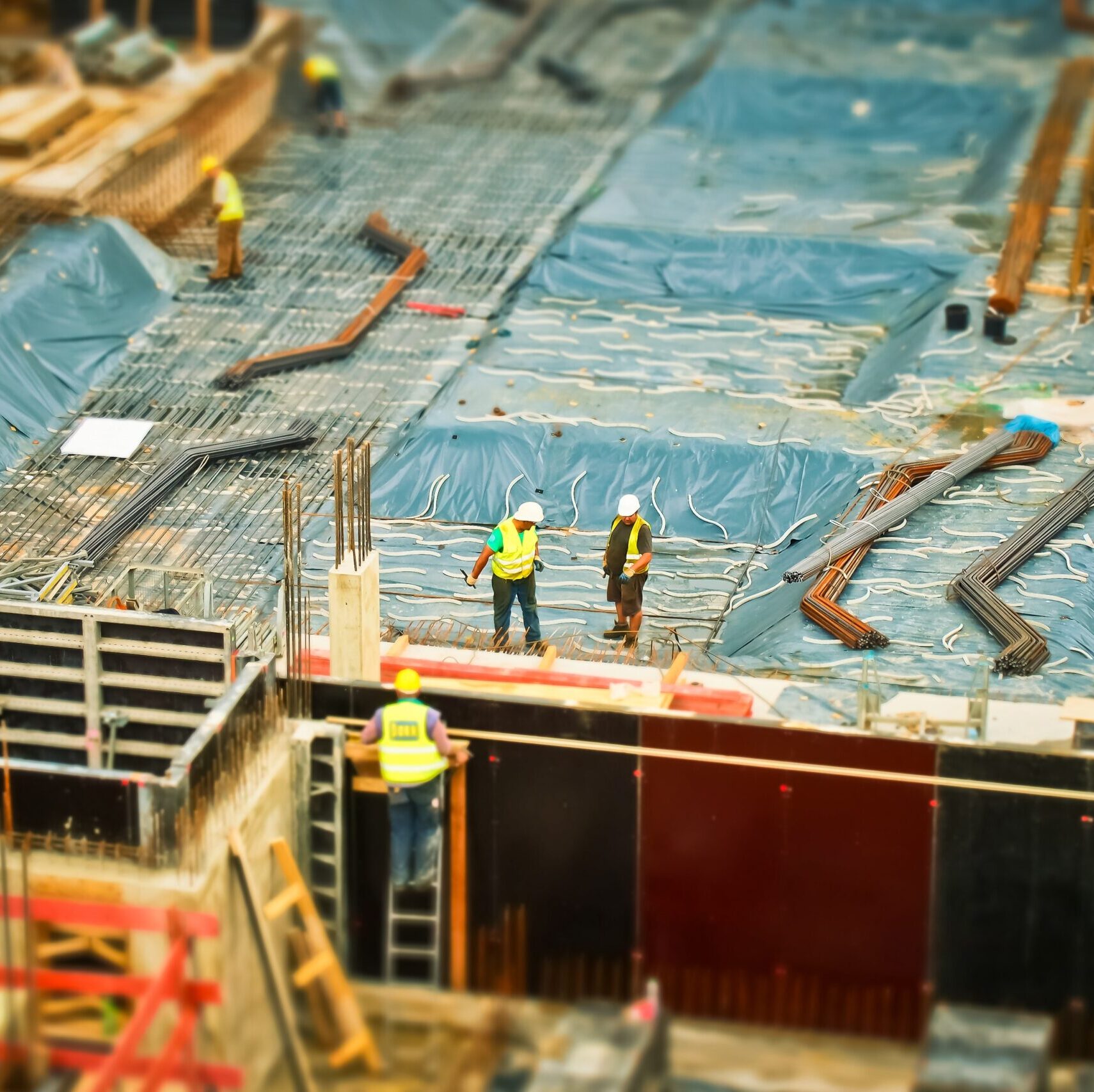 Construction site with workers in yellow safety vests on rebar foundation